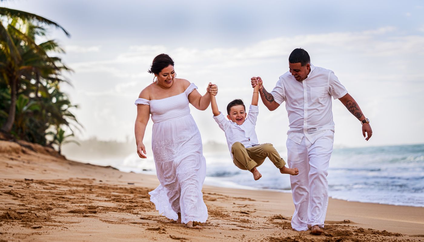 Parents swinging their laughing son on a beach